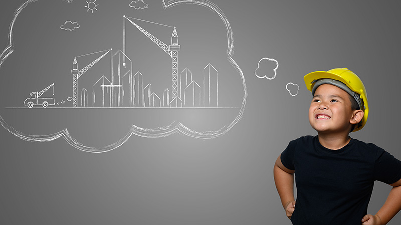Child wearing a hard hat and imagining buildings