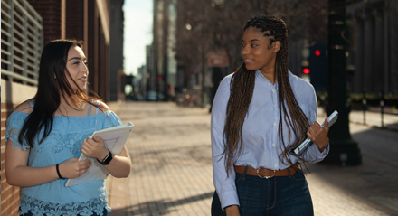 Two female UHD student walking down the sidewalk towards Commerce Street.