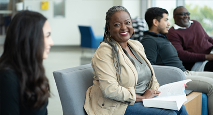 a female UHD student seated smiling at another student