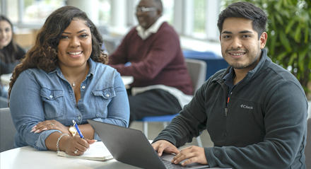 a male and female student sitting at a table in the UHD Welcome Center