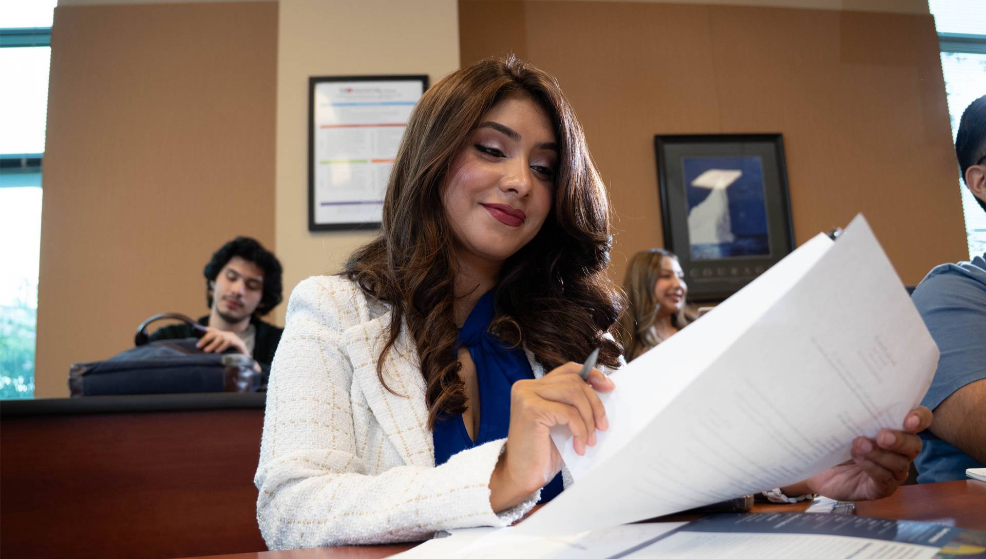 female UHD student in class looking through papers