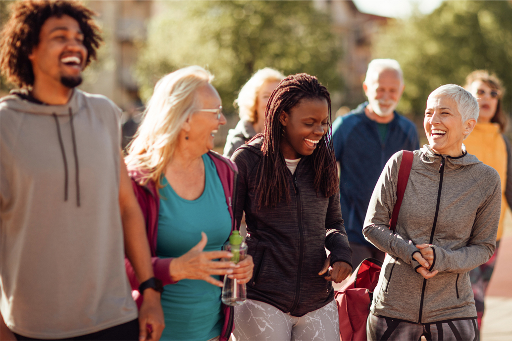 group of diverse adults outside walking together and laughing and smiling
