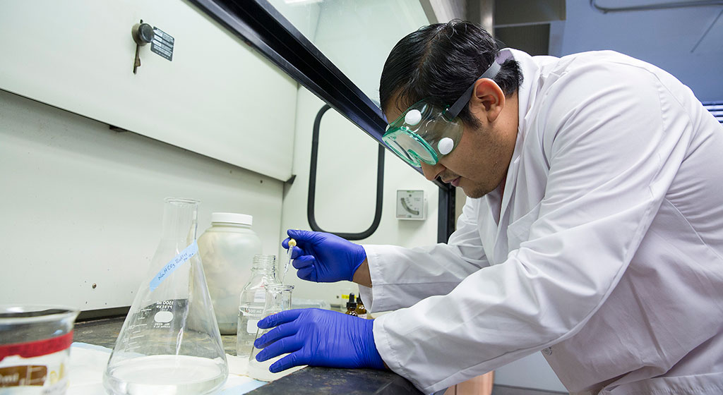 Lab tech adding sample to a container. Lab tech adding sample to a container.