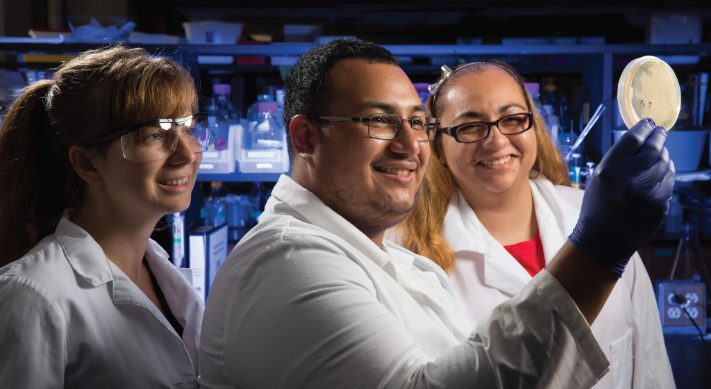 Image of three science students examining a specimen Image of three science students examining a specimen