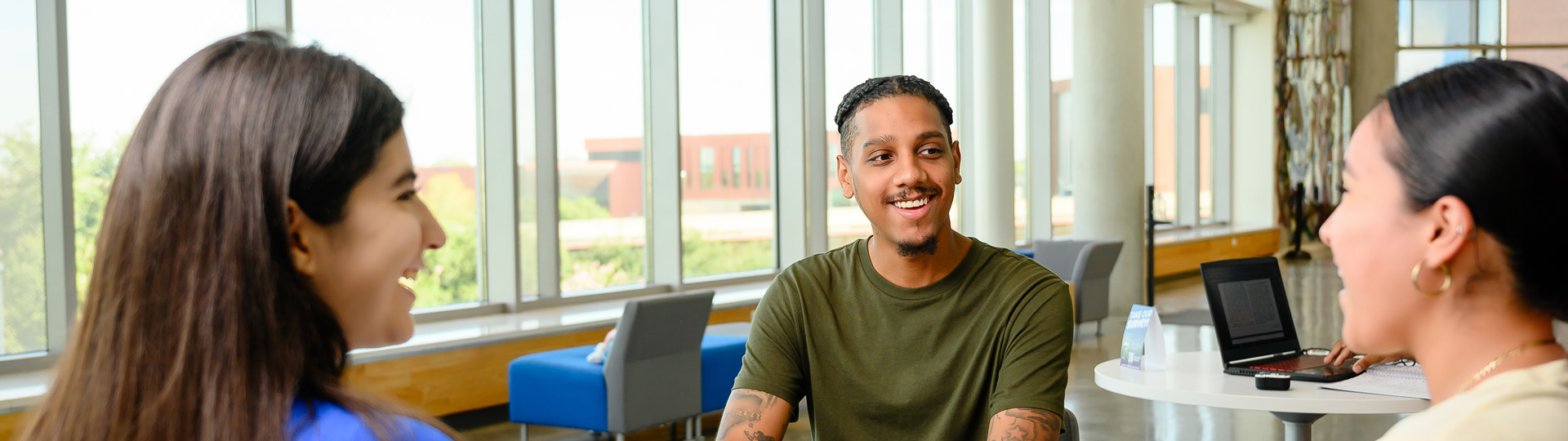 UHD students smiling and talking while sitting in the Welcome Center