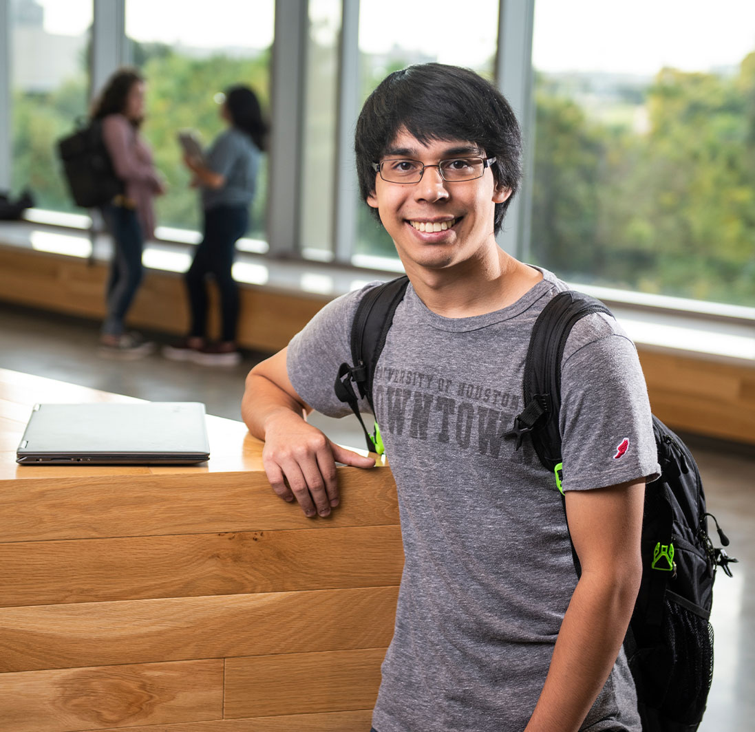UHD student posing with two students talking in the background