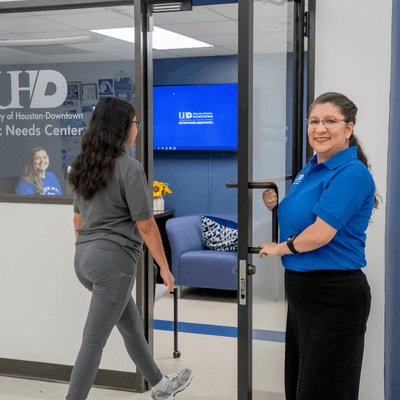 Hope Pacheco, Assistant Dean of Student Advocacy & Assistance, opens the door of the Basic Needs Center at UHD for a student while a staff member smiles in the office