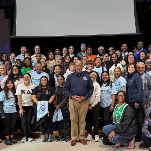 Faculty, staff, students and alumni from the university of houston downtown smile as a group at the university's gatorserve at dogan elementary school in houston independent school district.