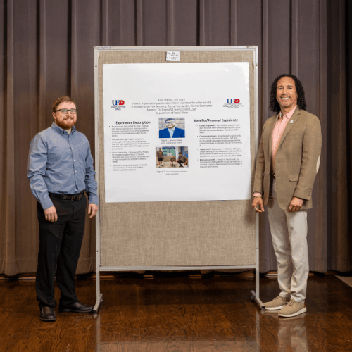Max von rettberg and college of public service dean José Ricardo-Osorio stands next to a research poster on the impact of policy on elderly inmates at the university of houston-downtown 