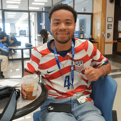 A student wears a United States soccer jersey while holding an ice coffee at the University of Houston-Downtown's food court 