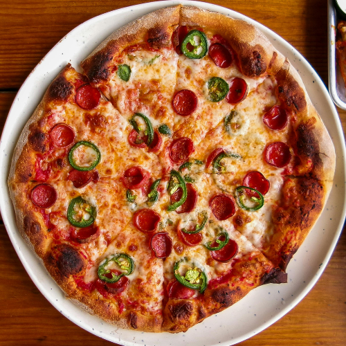 A pizza with jalapeno, cheese, and pepperoni on a plate