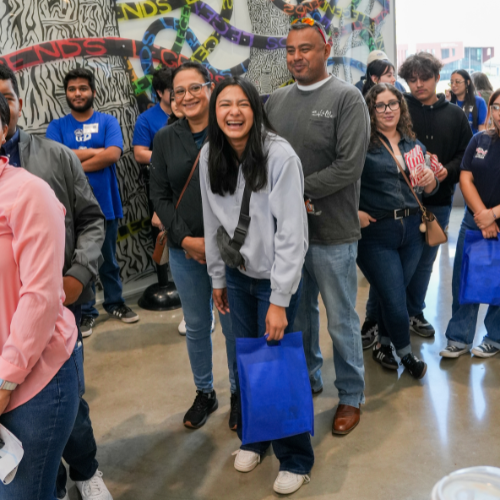 A student laughs while standing in line with families and prospective students at the University of Houston-Downtown's Open House 