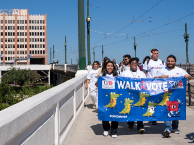 Students and staff from the university of houston-downtown hold a banner with the words walk2vote 