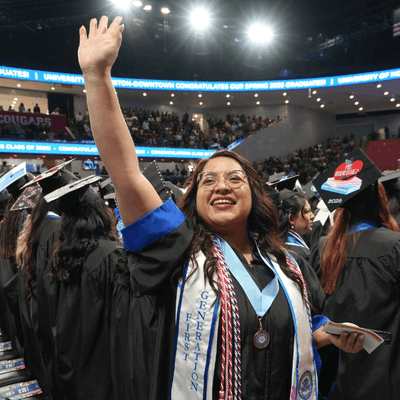 a 2026 University of Houston-Downtown graduate waves during the university's spring 2026 commencement ceremonies in houston, texas